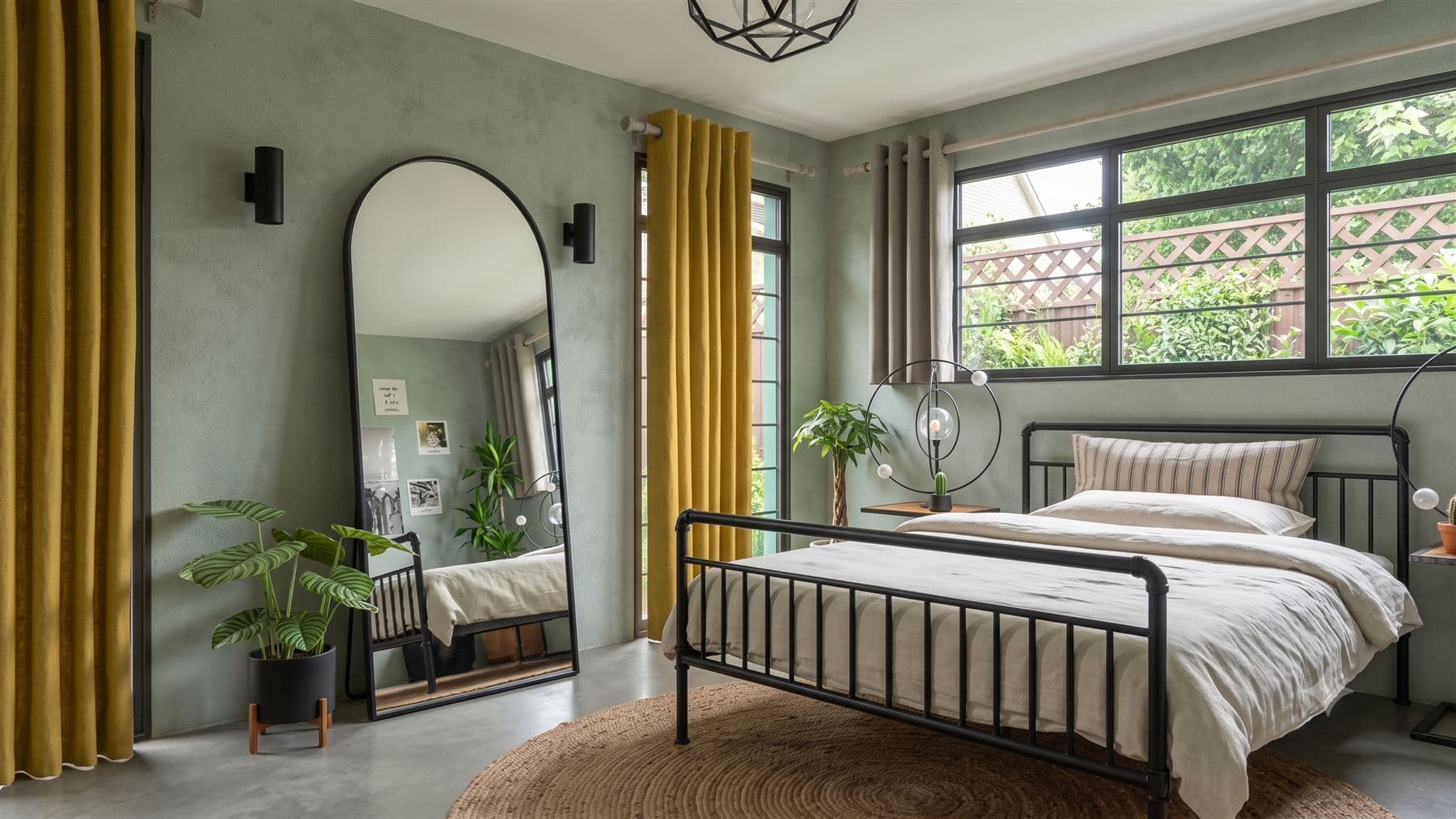 Dormitorio con paredes verde salvia, cortinas mostaza y espejo de arco